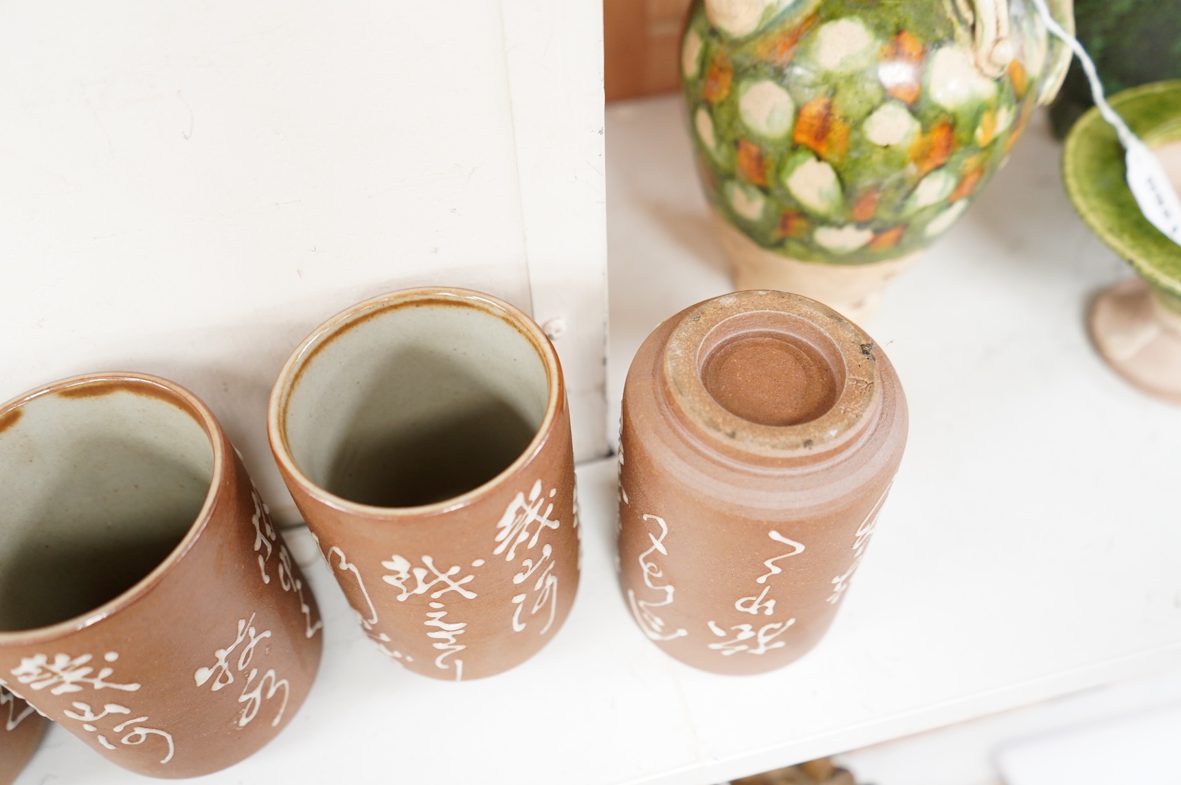 A set of four Japanese studio pottery beakers with calligraphy, 11cm high